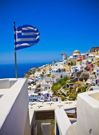 Amazing view on Oia city with waving Greek flagの写真素材