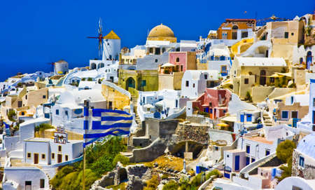 Amazing view on Oia city with waving Greek flagの写真素材