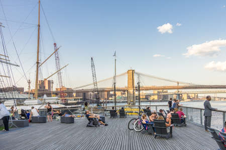 New York, NY - August 9th, 2014 : People relaxing on a pier on the East river with the Brookyln bridge and Manhattan bridge in the background in New York, USAのeditorial素材