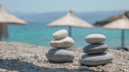 Two pebble towers with sun umbrellas on a sea shoreの写真素材