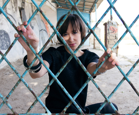 A girl behind the blue rusted bars