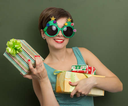 Beautiful woman holding Christmas presents on a yellow background with bokehの写真素材