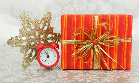 Christmas present and red clock on a snowy backgroundの写真素材