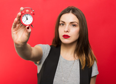 Beautiful woman holding red clockの写真素材