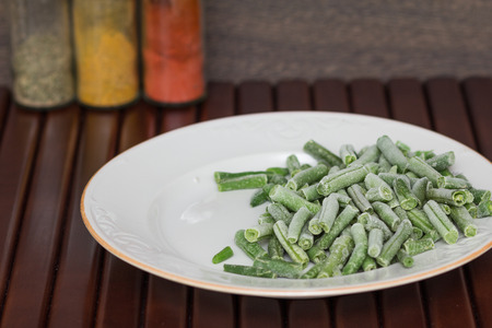 Green beans on a plate on a wooden background