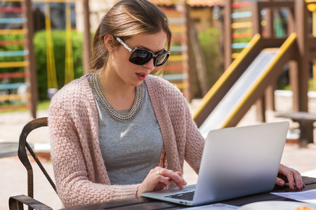 Young mother working at the laptop on a playgroundの写真素材