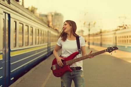 Girl with a guitar at train station. Retro toned imageの写真素材