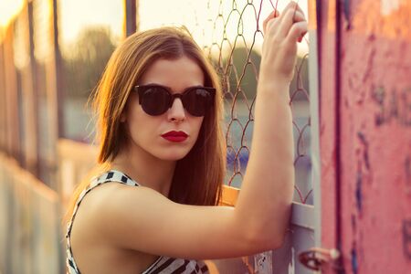 Lonely girl standing on the bridge. Retro toned imageの写真素材