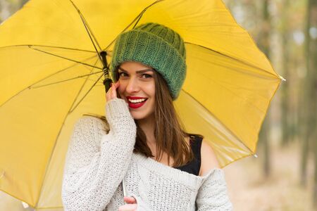 Lonely girl walking in the autumn park with a yellow umbrellaの写真素材