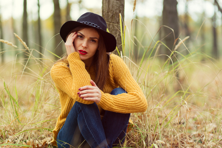 Lonely girl sitting in the autumn forestの写真素材