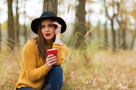 Lonely girl enjoying a cup of coffee in the forestの写真素材