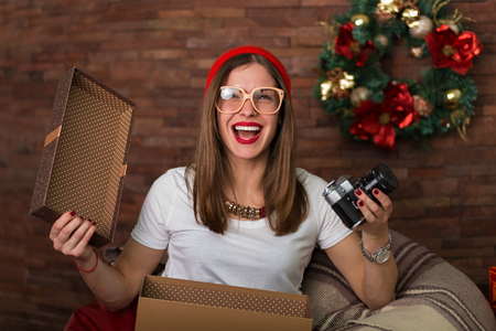 Pretty hipster woman opening her Christmas presentsの写真素材