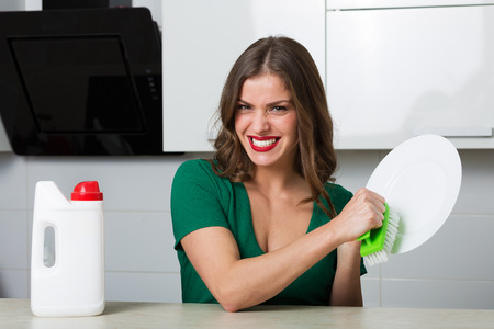Woman with washing detergent and a clean plateの写真素材