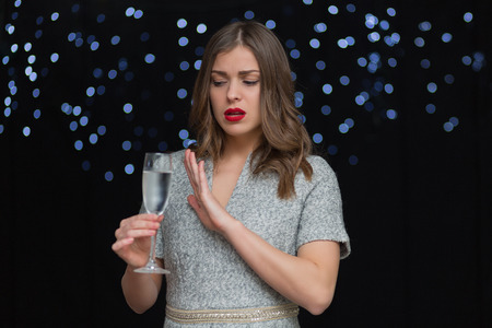 Beautiful woman with a glass of champagne on a black background with bokehの写真素材