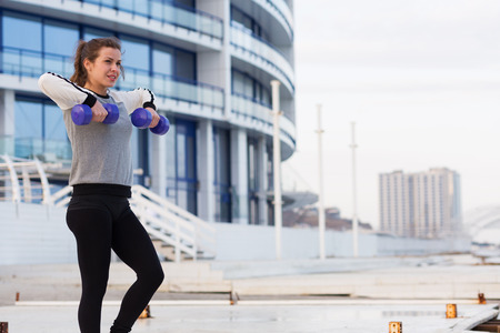 Sportive young woman working out outside in a big cityの写真素材