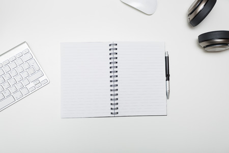 White desk in the office with notepad and headphones