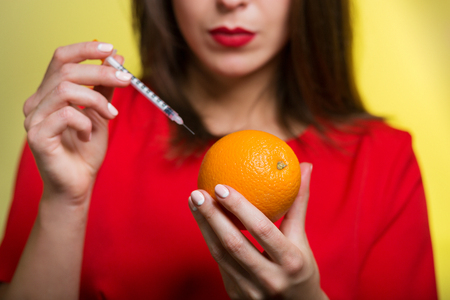 Woman holding a syringe and an orangeの写真素材