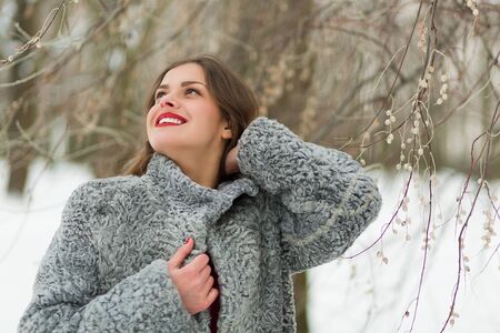 Beautiful woman in fur coat in the winter park