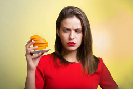 Woman in red dress holding slices of orangeの写真素材