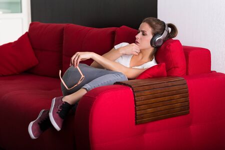 Young woman with headphones and mobile phone at her homeの写真素材