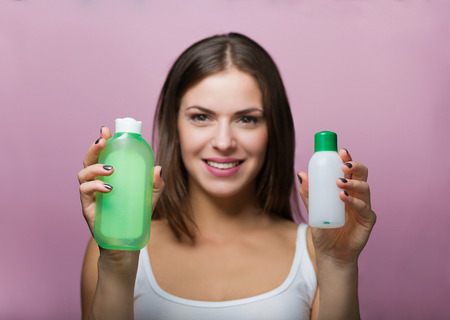 Pretty woman holding a bottle with a skin care productの写真素材