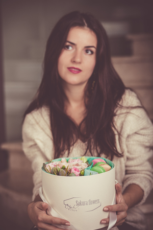 Pretty woman with a gift box with macaron cookiesの写真素材
