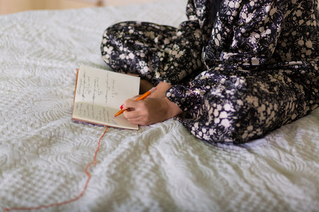 Woman with a diary sitting in her bedroomの写真素材