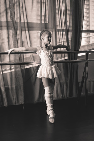 Little ballerina in a white dress in a dance studioの写真素材