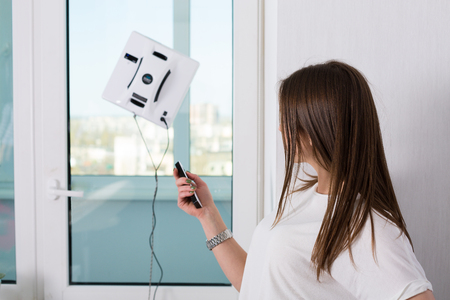Woman cleaning windows at home with robotic cleanerの写真素材