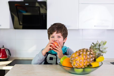 Little boy in the kitchen with a bowl of fresh fruitsの写真素材