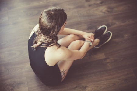 Sad young woman sitting on the floorの写真素材