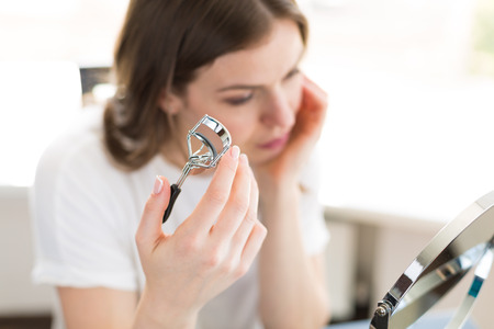 Woman applying make up sitting by the mirror