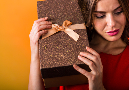 Beautiful woman in red dress holding a present box