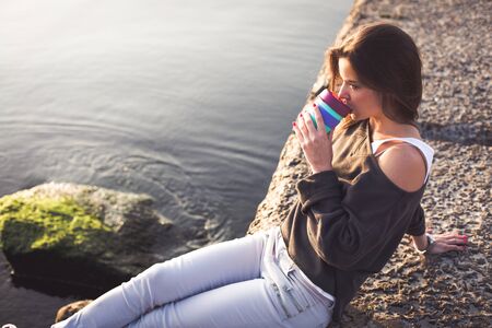Young woman drinking coffee on the beach in the morningの写真素材