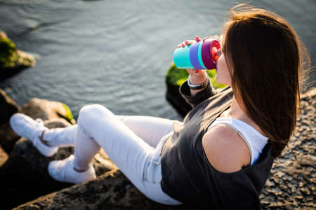 Young woman drinking coffee on the beach in the morning