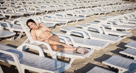 Beautiful woman lying on the sunbed tanning at the beach