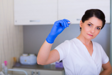 Woman cosmetologist with a brush and a cosmetic tweezers in the spaの写真素材