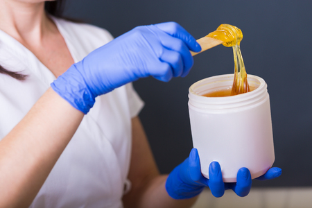 Woman cosmetologist working with sugar paste in a spa salonの写真素材