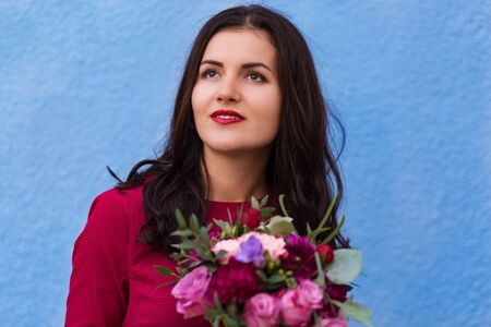 Beautiful bride in a red gown with a bridal bouquetの写真素材