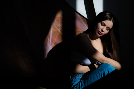 Young beautiful woman wearing jeans sitting on the floorの写真素材