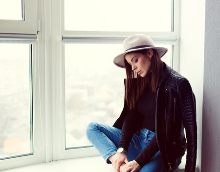 Beautiful boho woman in wool hat sitting by the windowの写真素材