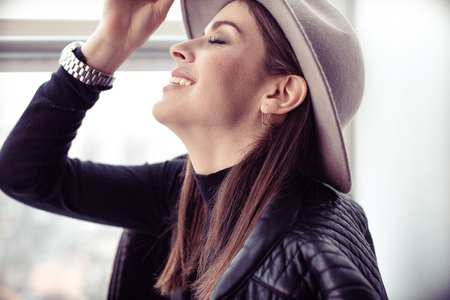 Beautiful boho woman in wool hat sitting by the windowの写真素材