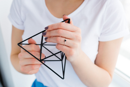 Beautiful young woman holding a black metal geometric decorの写真素材