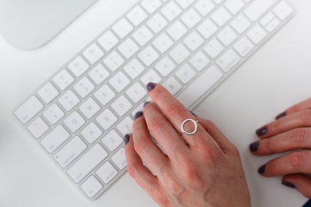 Woman with a ring typing on a keyboard at the officeの写真素材