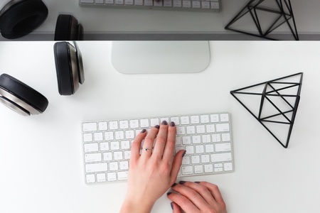 Workplace with a womans hands typing on a keyboard shot from aboveの写真素材