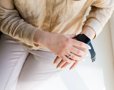 Young woman holding a smartwatch in her handsの写真素材