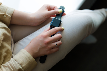 Young woman holding a smartwatch in her handsの写真素材