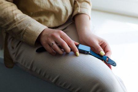 Young woman holding a smartwatch in her handsの写真素材
