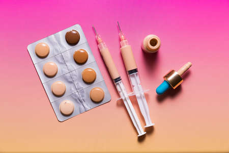 Pills in a blister pack and syringes filled with makeup concealer and foundation. Perfect skin conceptの写真素材