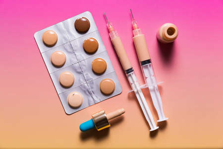 Pills in a blister pack and syringes filled with makeup concealer and foundation. Perfect skin conceptの写真素材